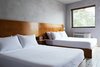 Modern home with Bedroom, Bed, Night Stands, Wall Lighting, and Ceramic Tile Floor. The Double Queen Guest Room's minimalist interiors include a custom, double platform bed, ceramic tile floors, and troweled concrete walls. Photo 7 of The Drifter Hotel