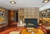Modern home with Living Room, Ceiling Lighting, Standard Layout Fireplace, Concrete Floor, Ottomans, Bench, Coffee Tables, and Wood Burning Fireplace. Living and dining spaces wrap around the full-height fireplace. Original light fixtures remain and have been outfitted with LED lights. Photo 4 of Frank Lloyd Wright's Eppstein House