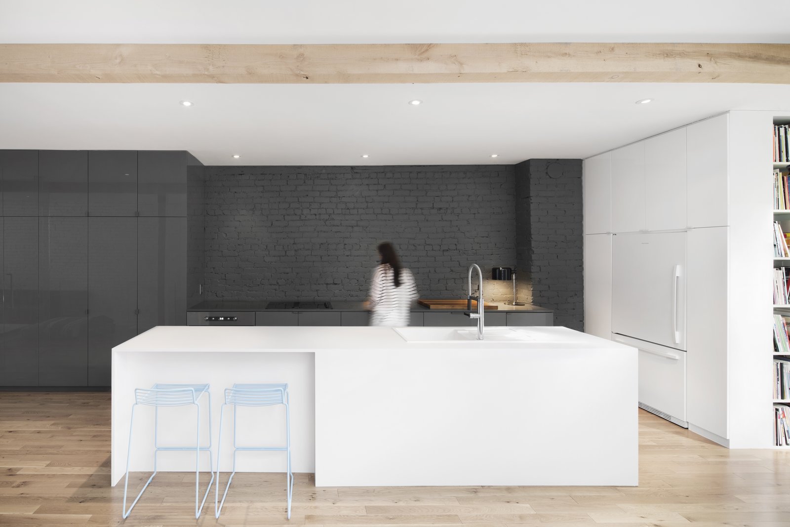 Gray, full-height, seamless cabinetry matches the gray-painted original brick wall. The contrast with the white kitchen island is striking.