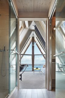 A full bath, framed by a glass shower enclosure and glass powder room enclosure, connects the two rooms on the third floor. The openness between the spaces draws the bay views inward.