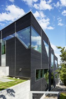 As you can see, the home follows the slope of the land. Geometric punched window openings draw in plentiful daylight.