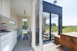 Bright interiors contrast to the dark exterior. Daylight fills the space via large glass doors and windows along each exterior wall.

