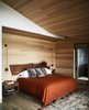 Modern home with Bedroom, Rug Floor, Light Hardwood Floor, Bed, Wall Lighting, and Night Stands. Warm, rustic colors make bold statements against the calming, natural palette. No detail goes unnoticed - even the headboard is a custom-made creation that embodies modern rusticity. Photo 6 of Caldera House