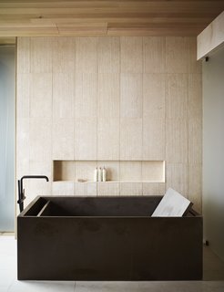 The rough texture of the tile walls adds a natural element to the refined, elegant bath.