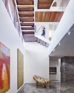 A open-tread staircase connects the below-grade gallery space to the living spaces above. Glass guardrails and the open treads allow for visual continuity and passage of light.