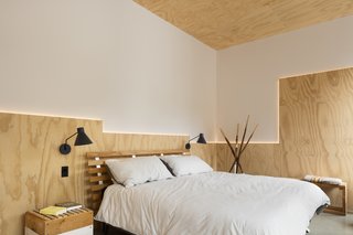 A geometric arrangement of back-lit plywood adds flair to a simple bedroom.