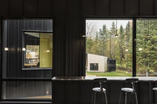 Built-in bar seating looks out upon the surrounding trees and into adjacent living spaces.