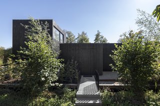 A simple boardwalk leads up to the timber-clad volume, which appears as a sculptural, black box upon entry. 