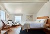 Modern home with Bedroom, Chair, Bed, Medium Hardwood Floor, Rug Floor, Shelves, Night Stands, Wall Lighting, and Accent Lighting. From the Shaws room, guests can enjoy both ocean and garden views while lounging on the chaise. Photo 11 of Hotel Joaquin