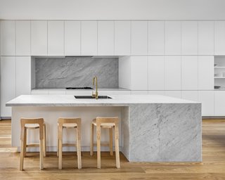 A large, marble island is the focal point of the all-white kitchen.