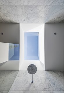 The skylight above provides a rhythm of light and shadow across the shower walls.