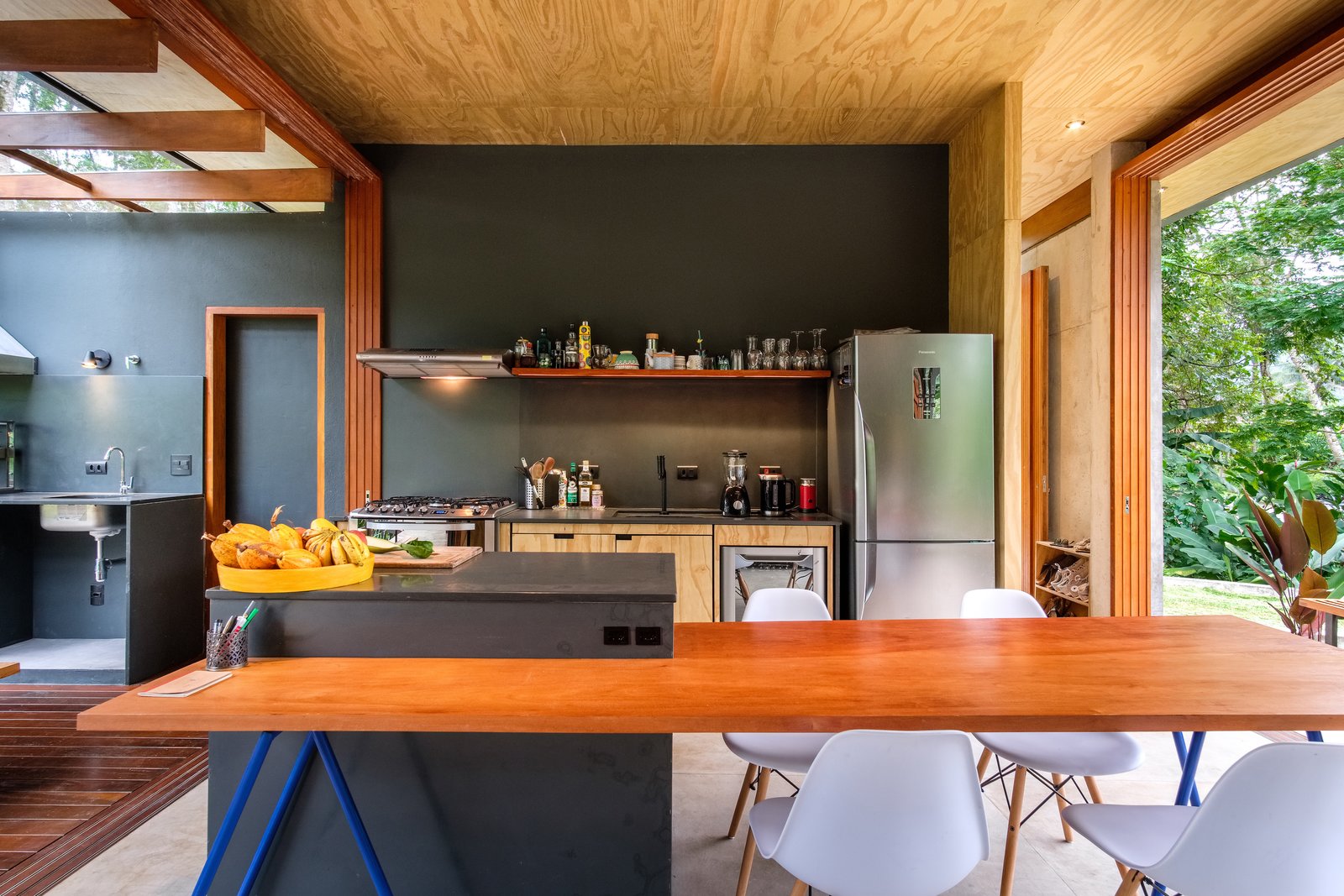 pittaarquitetura Cocina, piso de concreto, campana extractora, refrigerador, madera y estufa Grandes aberturas en ambos lados de los espacios de estar facilitan la ventilación natural. El hogar crea la sensación de estar al aire libre mientras proporciona refugio de los elementos.