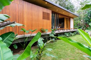 A layering of exterior elements—including sliding glass doors, a timber screen, and mobile timber panels—provides flexibility and climate control for the occupants.