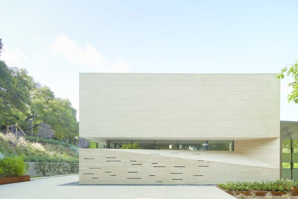 This opaque facade of dry-stacked, brush-hammered Hera limestone faces the neighbors uphill, providing privacy for the occupants.