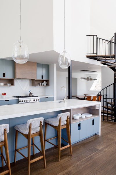 An open plan combines the cooking, dining, and living spaces. A color palette of natural woods, soft blues, creamy whites, and rust tones ties the spaces together.