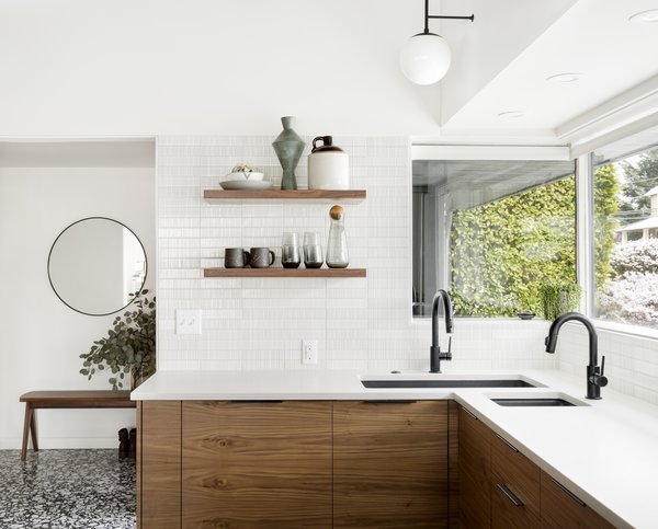 The sink configuration proved to be a tricky dilemma in this kitchen. A corner sink seemed to be the best solution for ample prep space and cabinet storage. With limited finish and cost options for a corner sink, the designers decided to pair two sinks together - a large single basin and a small bar sink - to maximize functionality and space.