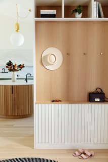 The entry hall is another snapshot of design experimentation with wood built-ins, open cubbies, and simple brass hooks. 