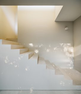 A white, geometric stair is a bright contrast to the black exterior. 