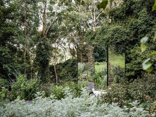 The one-way mirrored cube reflects the surrounding landscape, blurring the separation between architecture and site. Only the slight outline of the structure is visible. 