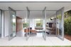 Modern home with Living Room, Chair, Sofa, Ottomans, Coffee Tables, Ceiling Lighting, Floor Lighting, Recessed Lighting, and Concrete Floor. Floor to ceiling glass doors pivot onto the back patio. Photo 2 of Santa Monica Residence