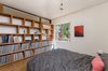 Modern home with Bed, Shelves, Storage, Pendant Lighting, Bookcase, Medium Hardwood Floor, Casement Window Type, Metal, and Bedroom. Bedroom with built-in wood shelves for records, etc. Clerestory above to allow natural light into bathroom beyond. Steel window with view to rear yard landscape. Art by Peggy Hsu Photo 10 of Boise Residence