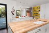 Modern home with Wood Counter, Engineered Quartz Counter, White Cabinet, and Kitchen. Kitchen at island with views of rear yard deck and dining room beyond Photo 6 of Allaseba Residence
