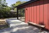 Modern home with Back Yard, Shrubs, Trees, Large Patio, Porch, Deck, Wood Patio, Porch, Deck, Decking Patio, Porch, Deck, Doors, Metal, Sliding Door Type, and Exterior. Detail of red standing seam metal siding with bench at raised deck and corner sliding door unit Photo 3 of Allaseba Residence