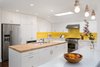 Modern home with Kitchen, Engineered Quartz Counter, Wood Counter, White Cabinet, Medium Hardwood Floor, Recessed Lighting, Pendant Lighting, Ceramic Tile Backsplashe, Range Hood, Refrigerator, Wall Oven, Range, Microwave, Dishwasher, and Undermount Sink. Kitchen at peninsula with island beyond Photo 8 of Allaseba Residence