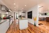 Modern home with White Cabinet, Medium Hardwood Floor, Stone Slab Backsplashe, Recessed Lighting, Engineered Quartz Counter, Refrigerator, Range, Range Hood, Microwave, Dishwasher, Undermount Sink, Sliding Window Type, Metal, Staircase, Wood Tread, and Glass Railing. Kitchen with island: Living Room, staircase, Dining Room and rear yard beyond Photo 8 of Bowling Green Residence