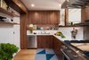 Modern home with Marble Counter, Wood Cabinet, Light Hardwood Floor, Marble Backsplashe, Recessed Lighting, Refrigerator, Range, Range Hood, Dishwasher, Undermount Sink, Wood, Interior, Swing Door Type, Kitchen, and Brick Backsplashe. Kitchen with American Black Walnut cabinets and Calacatta marble countertops open to Living Room on right. Original red brick exposed above backsplash Photo 4 of Ashland Residence