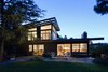 Modern home with Outdoor, Back Yard, Garden, Field, Woodland, Trees, Shrubs, Grass, Hardscapes, Flowers, Walkways, Large Patio, Porch, Deck, Wood Patio, Porch, Deck, Gardens, Decking Patio, Porch, Deck, Stone Patio, Porch, Deck, Horizontal Fences, Wall, and Landscape Lighting. Backyard elevation at dusk Photo 7 of Ridgemont Residence