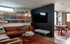 Modern home with Living Room, Recessed Lighting, Bookcase, Pendant Lighting, Concrete Floor, Chair, Coffee Tables, Floor Lighting, Ottomans, and Sofa. Family Room with bookshelves and a television disguised on the charcoal cement plaster wall that slips by the dining table sliding door beyond. This space opens onto the kitchen and dining and acts as a catchall gathering room to lounge before and after meals. Photo 6 of Ashland Residence