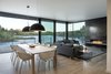 Dining room with large dome lights, corner window toward view and blackened steel clad fireplace. Photo 8 of Riverwood modern home