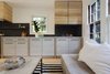 Modern home with Living Room, Sofa, Light Hardwood Floor, Gas Burning Fireplace, and Coffee Tables. A Tillary sectional sofa in bone faux suede and a Box Frame coffee table with a whitewashed-wood top, both from West Elm, outfit the seating area. Photo 5 of Live-in Kitchen