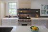 Modern home with Kitchen, Wood Cabinet, Light Hardwood Floor, Laminate Cabinet, White Cabinet, Stone Tile Backsplashe, Wall Oven, Recessed Lighting, Refrigerator, and Dishwasher. Aamodt chose a honed black stone material called Basaltina for the backsplash, shelf, and fireplace surround to contrast with the cabinets. Its asymmetric composition — the stone steps down as it moves away from the work area of the kitchen — adds a bit of quirkiness to the soothing aesthetic. Photo 8 of Live-in Kitchen