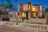 Modern home with Outdoor, Trees, Hardscapes, Front Yard, Gardens, Walkways, Flowers, Horizontal Fences, Wall, Raised Planters, Vertical Fences, Wall, Wood Fences, Wall, and Landscape Lighting. Front Exterior, Night Photo of The Rosewood Residence