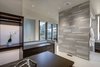 Modern home with Bath Room, Wood Counter, Porcelain Tile Floor, Drop In Sink, Freestanding Tub, Enclosed Shower, Ceiling Lighting, Recessed Lighting, Wall Lighting, Accent Lighting, Porcelain Tile Wall, and Two Piece Toilet. The thoughtful selection of lighting and materials fashions a spa like oasis. Photo 7 of Two Creeks