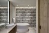 Modern home with Bath Room, Engineered Quartz Counter, Porcelain Tile Floor, Vessel Sink, Freestanding Tub, Enclosed Shower, Ceiling Lighting, Recessed Lighting, Accent Lighting, Wall Lighting, Porcelain Tile Wall, Two Piece Toilet, and Soaking Tub. The thoughtful selection of lighting and materials fashions a spa like oasis. Photo 14 of Two Creeks