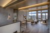 Modern home with Living Room, Two-Sided Fireplace, Chair, Ottomans, Coffee Tables, Recessed Lighting, Accent Lighting, End Tables, and Medium Hardwood Floor. The grand entry opens onto to the spacious great room with sizable windows, and a 16-foot folding wall system out to a deck ideal for entertaining or even stargazing. Photo 2 of Two Creeks
