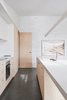 Modern home with Kitchen, Stone Counter, Wood Cabinet, Concrete Floor, Ceramic Tile Backsplashe, Ceiling Lighting, Pendant Lighting, Accent Lighting, Wall Lighting, Refrigerator, Wall Oven, Cooktops, and Drop In Sink. Kitchen featuring custom sustainable joinery by The Nest, recycled brick wall with no VOC paint, and photography by Brooke Holm (represented by Modern Times). Photo 3 of The 10 Star Home