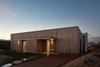 Modern home with Outdoor, Front Yard, Shrubs, Grass, Gardens, Walkways, Vegetables, Pavers Patio, Porch, Deck, Stone Patio, Porch, Deck, and Landscape Lighting. The 10-Star Home is a design collaboration between Clare Cousins Architects and The Sociable Weaver. The shapely exterior blends into the surrounding landscape. Photo of The 10 Star Home