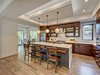Modern home with Kitchen, Engineered Quartz Counter, Light Hardwood Floor, Ceramic Tile Backsplashe, Glass Tile Backsplashe, Accent Lighting, Ceiling Lighting, Refrigerator, Wood Cabinet, Wall Oven, Microwave, Range Hood, Range, and Undermount Sink. Kitchen with custom cabinets, LED uplighting, and herringbone glass backsplash Photo 6 of Contemporary Craftsman Home
