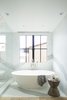 Modern home with Bath Room, Stone Slab Wall, Light Hardwood Floor, and Freestanding Tub. The master bathroom is another example of the intersection of rustic, raw materials, paired with the glamor of an oversized calacatta slab and a contemporary tub. Photo 6 of Manhattan Ave Residence