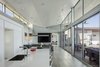 Modern home with Living Room, Sofa, Pendant Lighting, Ceramic Tile Floor, Sectional, Coffee Tables, Ceiling Lighting, Ribbon Fireplace, Two-Sided Fireplace, and Gas Burning Fireplace. main public wing looking toward the living area from the kitchen Photo 6 of The U V House