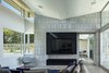 Modern home with Living Room, Chair, Sofa, Sectional, Coffee Tables, Ceiling Lighting, Ceramic Tile Floor, Ribbon Fireplace, Two-Sided Fireplace, and Gas Burning Fireplace. living area focal wall, featuring the ribbon fireplace/TV detail, limestone veneer and sloped ceiling Photo 7 of The U V House