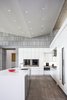 Modern home with Kitchen, Engineered Quartz Counter, White Cabinet, Ceramic Tile Floor, Ceiling Lighting, Wall Oven, Cooktops, Range Hood, Microwave, Refrigerator, Wine Cooler, and Undermount Sink. Kitchen detail featuring, the back-lit back splash and limestone veneer Photo 9 of The U V House