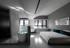 Modern home with Bedroom, Ceiling Lighting, Marble Floor, Bed, and Concrete Floor. The bathtub splits from the bathroom and is separately located in the middle, diverting the circulation around it. Photo 8 of Fluid House