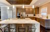 Modern home with Kitchen, Dark Hardwood Floor, Wood Cabinet, Engineered Quartz Counter, Stone Slab Backsplashe, Recessed Lighting, Refrigerator, Cooktops, Pendant Lighting, Range, Dishwasher, and Drop In Sink. The kitchen features Cambria quartz countertops and a custom finish on the cabinetry. Photo 2 of Modern Infusions