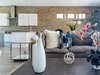 Modern home with Living Room, Sectional, Pendant Lighting, Coffee Tables, Ceiling Lighting, and Porcelain Tile Floor. Brick wall runs the length of the room through the dinning room into the kitchen. Photo 5 of Vegas Luxe