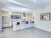 Modern home with Kitchen, Stone Tile Backsplashe, Engineered Quartz Counter, White Cabinet, Concrete Floor, Refrigerator, Range, Ice Maker, Range Hood, Undermount Sink, Ceiling Lighting, Dishwasher, and Track Lighting. Kitchen Photo 2 of Stunning Eichler Remodel